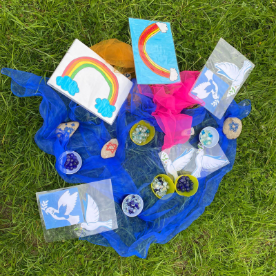 Selbst gestaltete Symbole des Erinnern, Gedenkens und des Friedens liegen auf einem blauen Tuch in der Wiese. GEH.DENKEN 2025 © VS Ansfelden